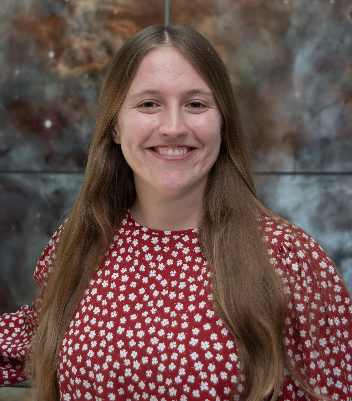 Photo of Michele Woodland in front of a space background.